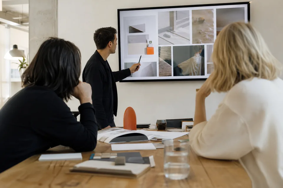Agency creative director presenting a design moodboard on a large screen to two clients