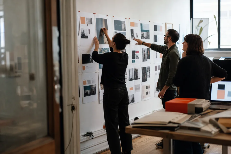 Product design team pinning printed website design inspiration on a wall